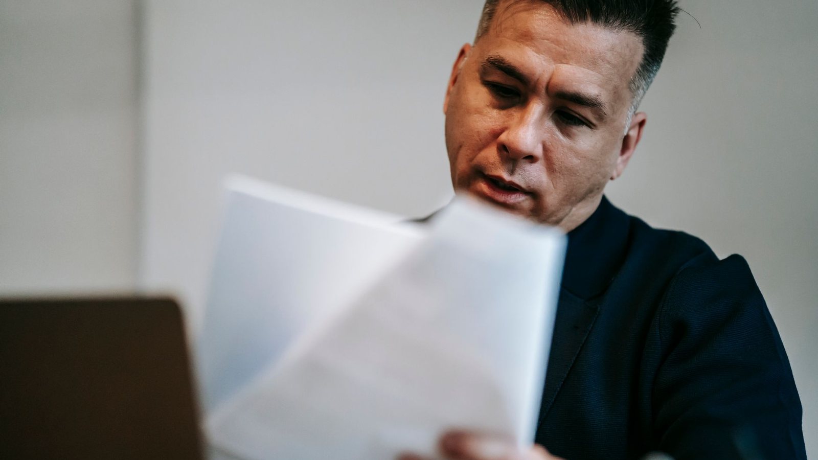 A man at his workstation going through printed paperwork, the return-filing work a fiscal representative takes over.